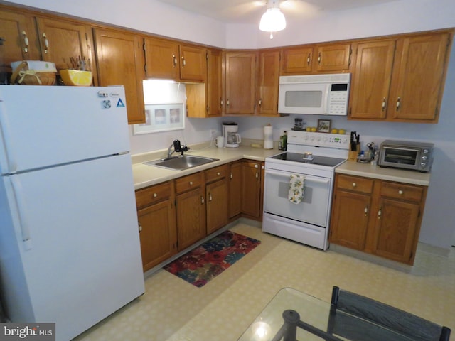 kitchen featuring light floors, white appliances, a sink, and light countertops