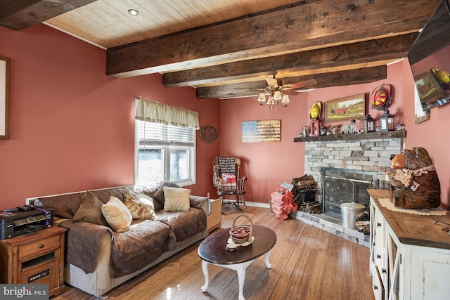 living area featuring baseboards, wooden ceiling, wood finished floors, beamed ceiling, and a fireplace