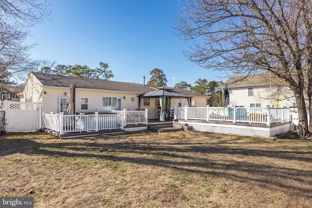 back of property with a gazebo, fence, a deck, and a yard