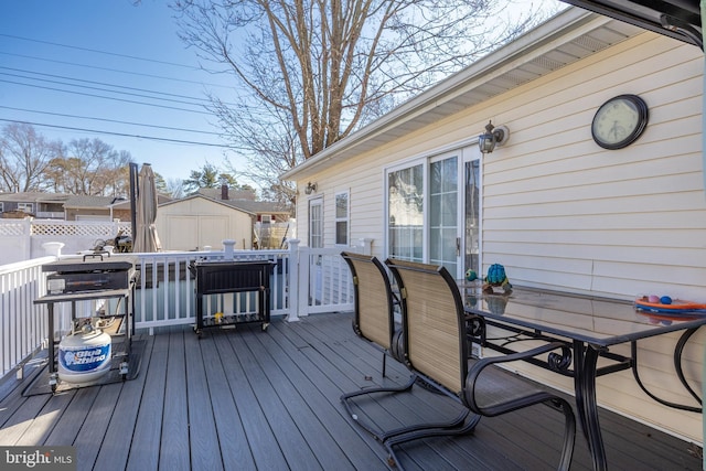 wooden deck with a storage shed, outdoor dining area, an outdoor structure, and fence