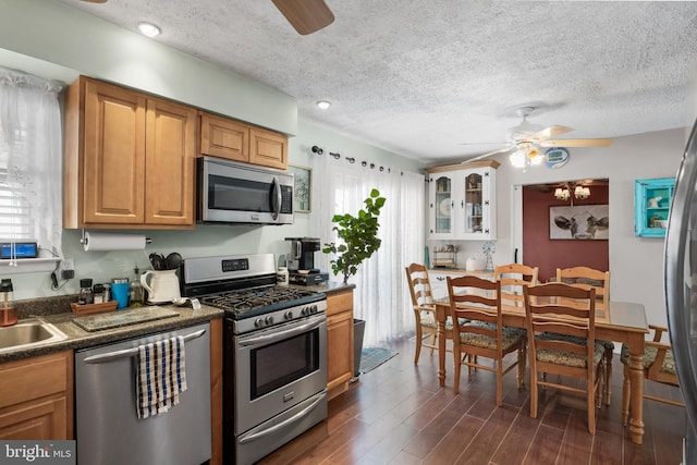 kitchen featuring stainless steel appliances, dark countertops, dark wood finished floors, and ceiling fan