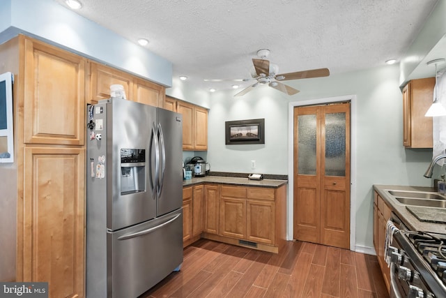 kitchen featuring dark wood finished floors, appliances with stainless steel finishes, a ceiling fan, a sink, and a textured ceiling