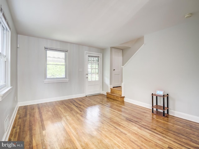 empty room with visible vents, stairway, light wood-style floors, and baseboards