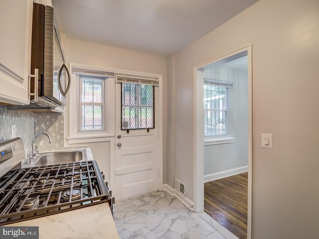 kitchen with visible vents, decorative backsplash, appliances with stainless steel finishes, marble finish floor, and a sink