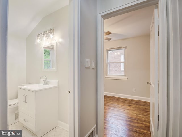 bathroom with baseboards, toilet, lofted ceiling, wood finished floors, and vanity