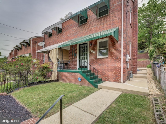 view of front facade with a front yard, fence, and brick siding