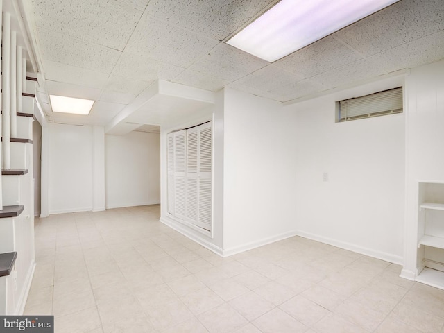 finished below grade area with baseboards and a paneled ceiling