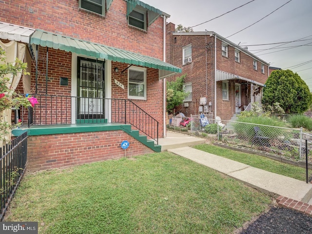 exterior space with brick siding, a front yard, and fence