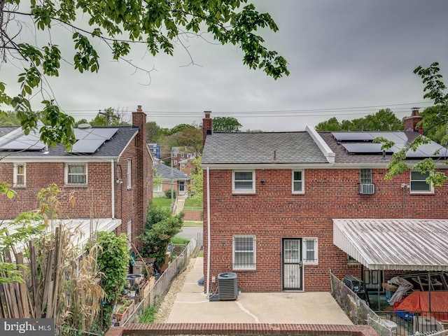 exterior space featuring brick siding, roof mounted solar panels, a patio area, and cooling unit