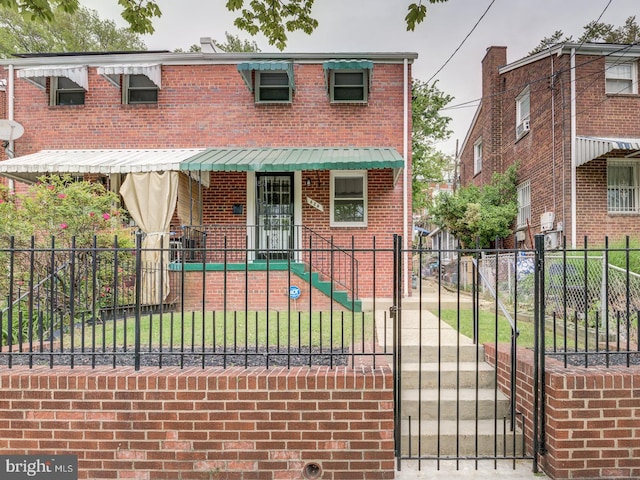 view of front of home featuring a fenced front yard, brick siding, covered porch, and a gate