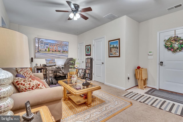 living area featuring baseboards, ceiling fan, visible vents, and light colored carpet