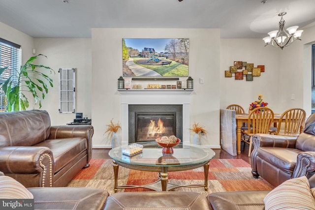 living area featuring baseboards, a chandelier, wood finished floors, and a glass covered fireplace