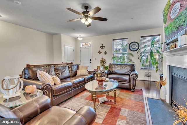 living area featuring wood finished floors, a fireplace with flush hearth, and a ceiling fan