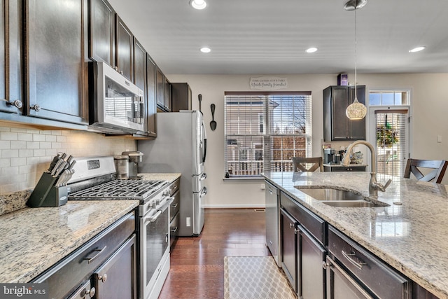 kitchen featuring dark wood-style floors, stainless steel appliances, decorative backsplash, a sink, and dark brown cabinets