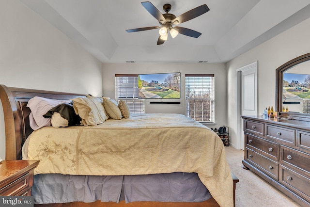 bedroom featuring a ceiling fan, a tray ceiling, light carpet, and visible vents