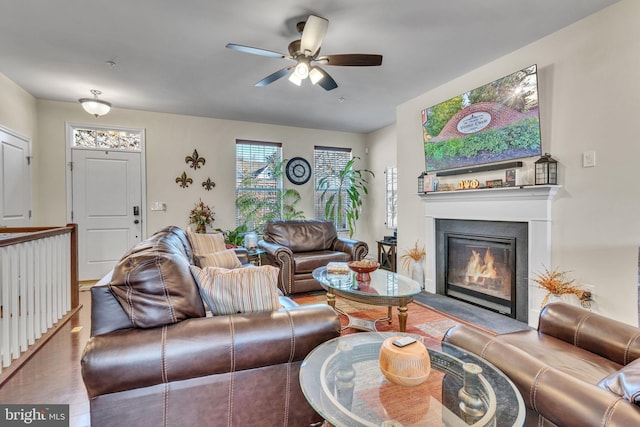 living area featuring ceiling fan, wood finished floors, and a glass covered fireplace