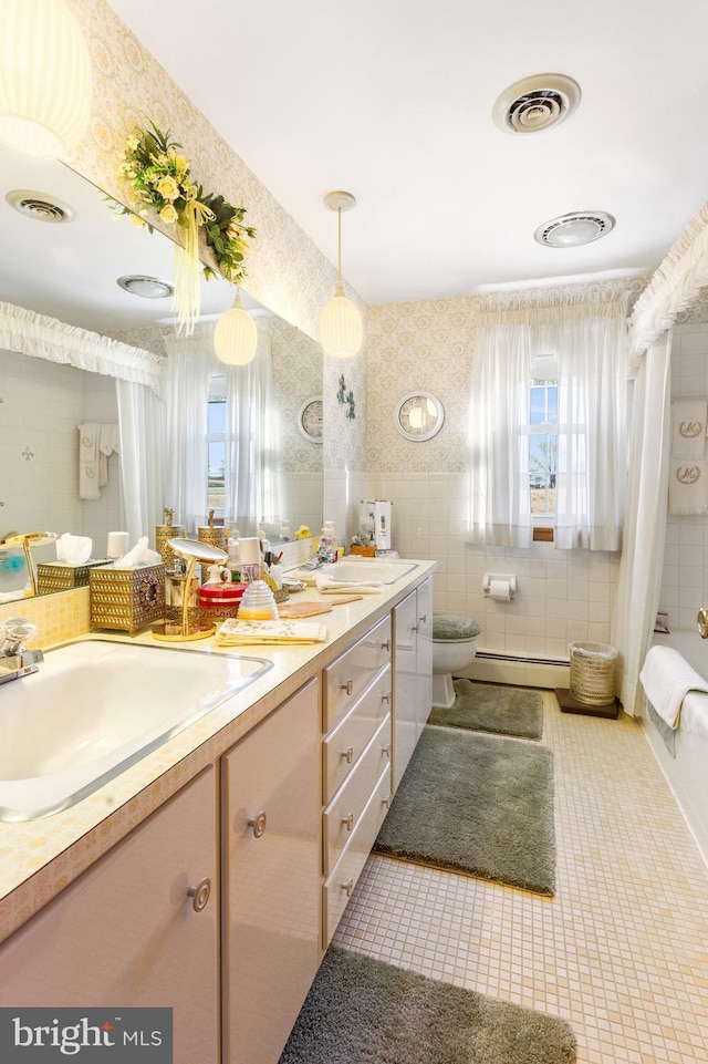 full bathroom featuring wallpapered walls, vanity, visible vents, and a baseboard radiator