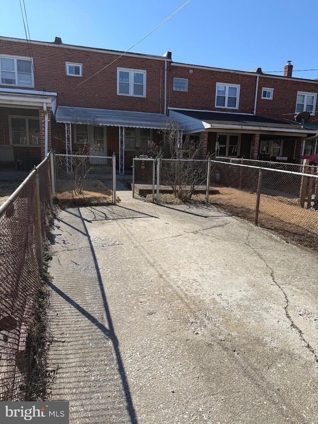 back of house with a fenced front yard, brick siding, and driveway