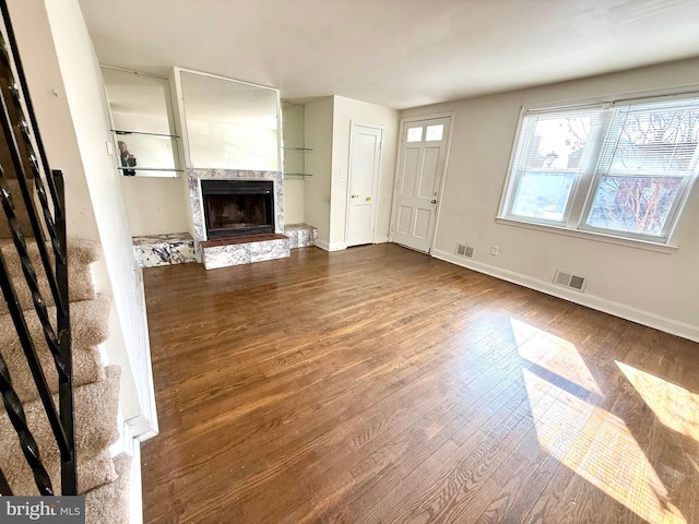 unfurnished living room featuring visible vents, a fireplace, baseboards, and wood finished floors