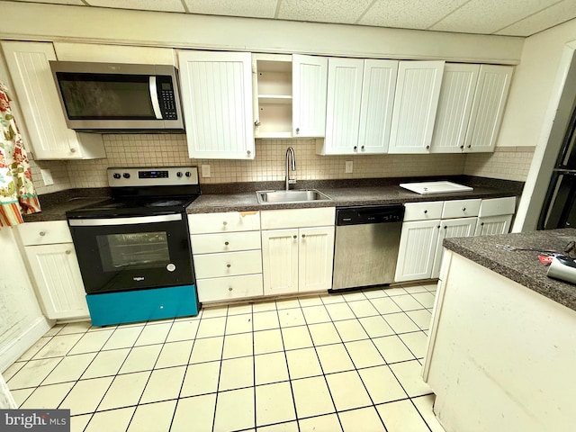 kitchen featuring dark countertops, appliances with stainless steel finishes, decorative backsplash, and a sink