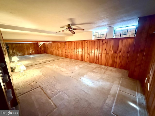 bonus room with a ceiling fan, carpet, and wooden walls