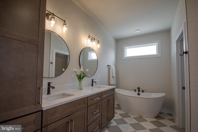 full bathroom with a sink, a freestanding tub, double vanity, and tile patterned floors