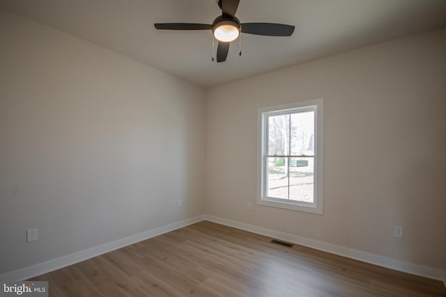 spare room featuring visible vents, baseboards, and wood finished floors