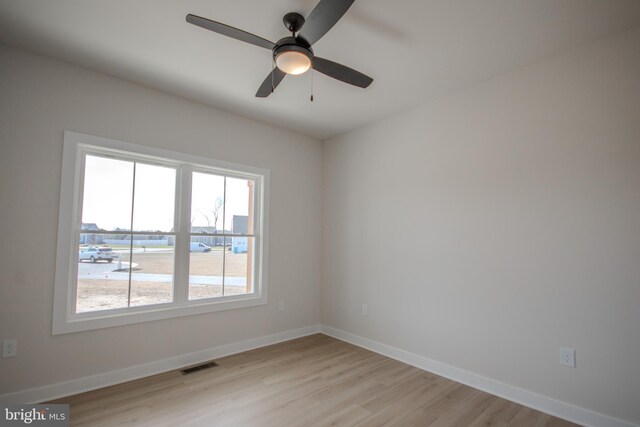 spare room featuring plenty of natural light, baseboards, visible vents, and light wood finished floors