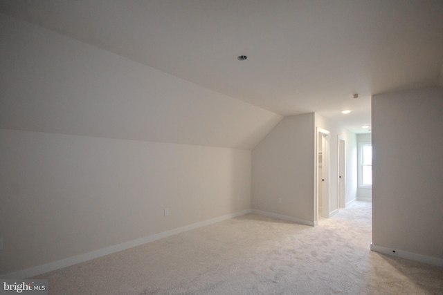 additional living space featuring baseboards, lofted ceiling, and light colored carpet