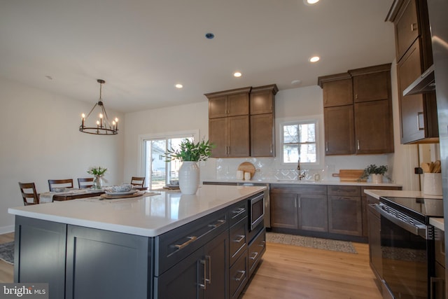 kitchen with light wood finished floors, electric range, recessed lighting, a sink, and light countertops