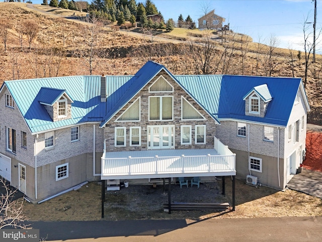 view of front of house with metal roof, a deck, an attached garage, and a standing seam roof