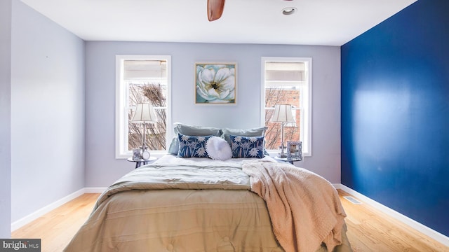 bedroom featuring multiple windows, baseboards, and wood finished floors