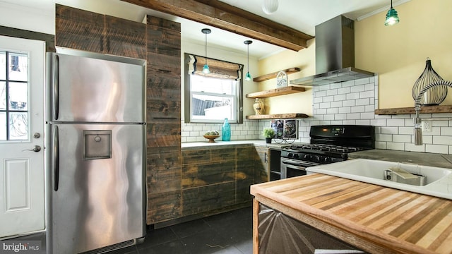 kitchen featuring tasteful backsplash, freestanding refrigerator, island exhaust hood, beam ceiling, and gas stove