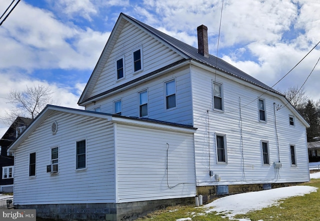 back of house with cooling unit, a chimney, and metal roof