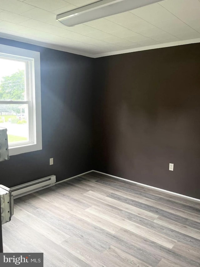 spare room featuring baseboard heating and wood finished floors