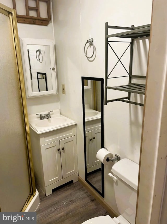 full bathroom featuring a shower with shower door, toilet, wood finished floors, and vanity