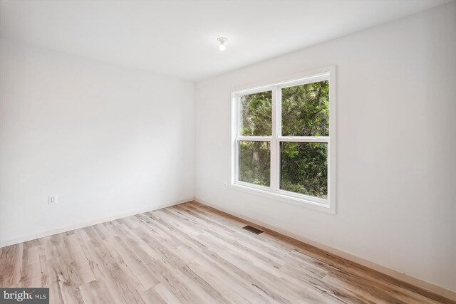 unfurnished room with visible vents, baseboards, and wood finished floors