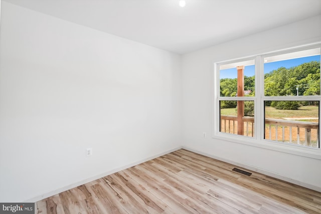 empty room featuring wood finished floors, visible vents, and baseboards