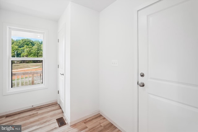 doorway to outside with plenty of natural light, visible vents, light wood-type flooring, and baseboards