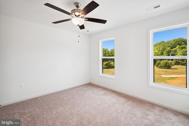 carpeted empty room featuring visible vents, ceiling fan, and baseboards