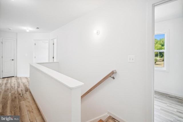 hallway featuring an upstairs landing, light wood finished floors, and baseboards