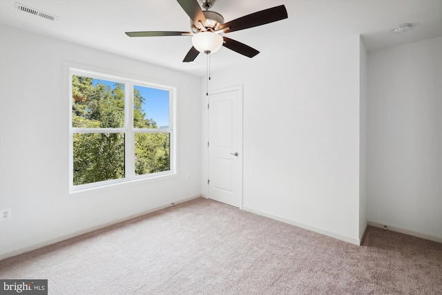 unfurnished bedroom featuring visible vents, light colored carpet, baseboards, and ceiling fan