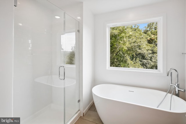 full bathroom featuring tile patterned flooring, a shower stall, and a freestanding bath