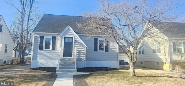 view of front facade featuring entry steps, a front lawn, a garage, and roof with shingles