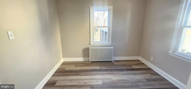 spare room with baseboards, wood finished floors, and radiator heating unit