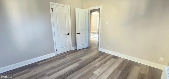 interior space with baseboards, arched walkways, and wood finished floors