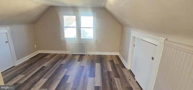 additional living space featuring baseboards, radiator heating unit, dark wood-type flooring, and vaulted ceiling