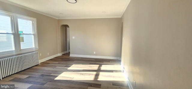 unfurnished room featuring crown molding, radiator, wood finished floors, and arched walkways