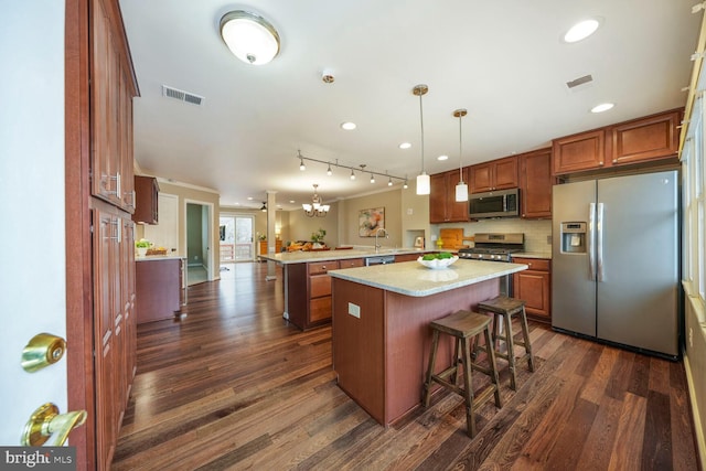 kitchen featuring visible vents, appliances with stainless steel finishes, dark wood-type flooring, and a peninsula