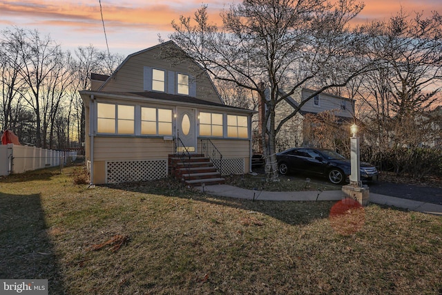 dutch colonial with entry steps, a yard, fence, and a gambrel roof